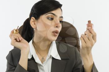 Businesswoman applying nail paint on fingernails in an office