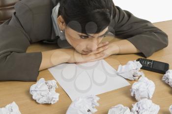 Businesswoman staring crumpled papers on her desk