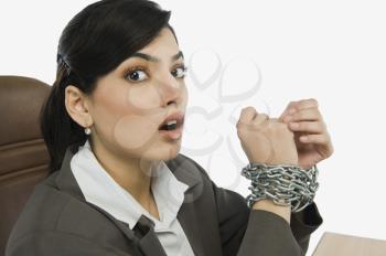 Businesswoman's hands tied up with a chain