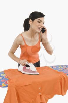 Woman ironing and talking on a mobile phone