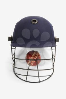 Close-up of a cricket ball under a cricket helmet