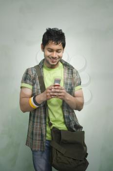 University student text messaging on a mobile phone and smiling