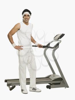 Portrait of a man standing beside a treadmill