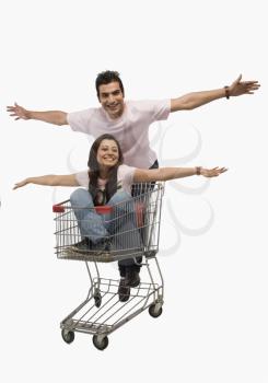 Man pushing a woman sitting in shopping cart