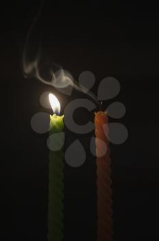Close-up of a lit candle with an extinguished candle