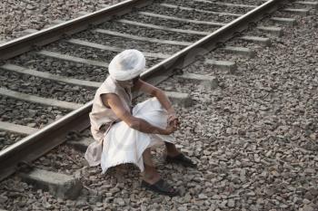 Man sitting near railroad track, Ahmedabad, Gujarat, India
