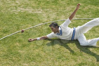 Cricket fielder diving to stop a ball near boundary line