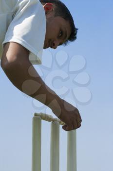 Cricket player adjusting bails on stumps