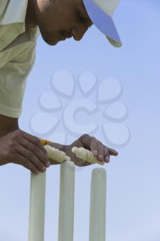 Cricket player adjusting bails on stumps
