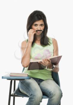 University student holding a pen on her lips as mustache