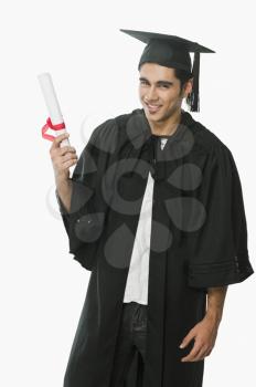 Man in a graduation gown holding a diploma