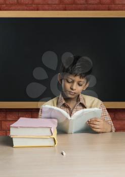 Boy imitating a teacher and reading a book in a classroom