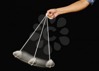 Close-up of a person's hand swinging a stone pendulum