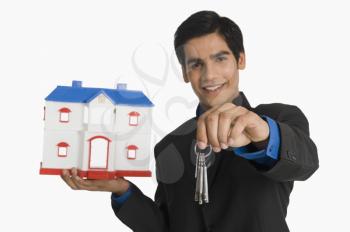 Real estate agent holding house keys and a model home