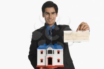 Real estate agent holding a model home and a check