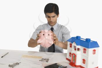 Real estate agent looking into a piggy bank