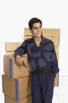 Store incharge leaning against cardboard boxes in a warehouse