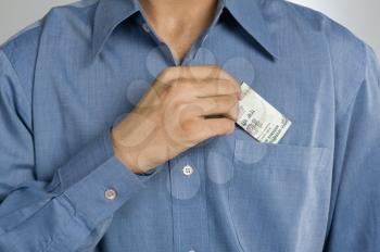 Mid section view of a man putting money in shirt pocket