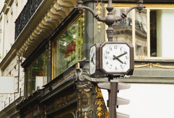 Clocks on a pole in front of a building, Paris, France