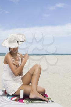 Woman applying suntan lotion on the beach