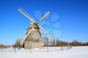 aging wind mill on winter field 