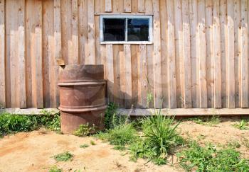 rusty barrel near wooden shed