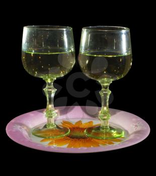 Two glasses of wine standing on a tray, on a black background. 
                   