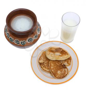 Milk in a jug and a glass, pancakes on a white background.                   