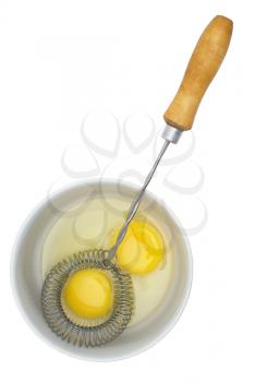 Crude eggs in a plate and mixer with the wooden handle on a white background.                   