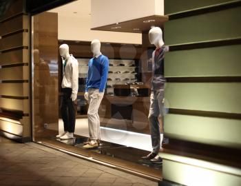 Night shop window with men dressed mannequins. Evening warm lihgt.