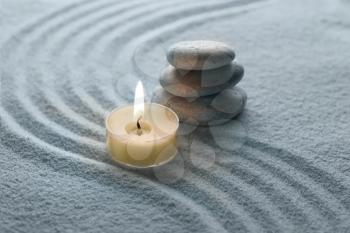 light warm candle and cool stone on sand 