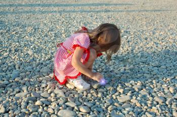 The little girl on a stony beach at the sea