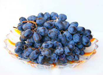 Ripe grape on plate on white background