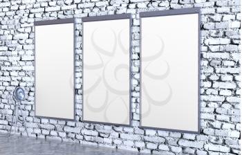 Three blank metal posters on a brick wall with lighting device. 3D illustration