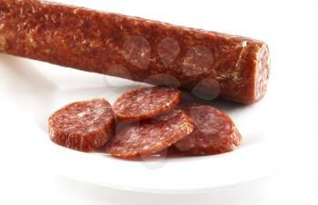 Smoked sausage cut by slices on a white dish
