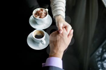 Royalty Free Photo of a Couple Holding Hands While Having Coffee