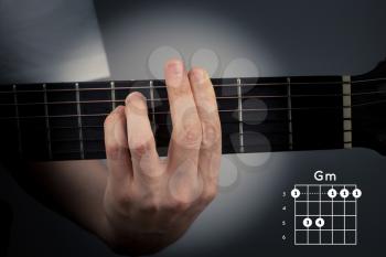 Guitar chord on a dark background with spot light. G Minor Chord. Gm tab fingering
