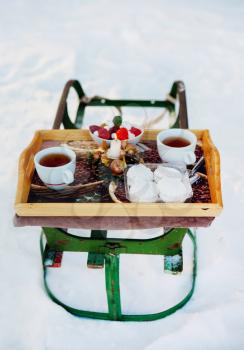 Romantic breakfast in the snow. Winter Vintage Sledge. Coffee, marshmallows, and other sweets in a compartment with a burning candle