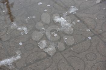 Remains of snow melt in a puddle on the sidewalk