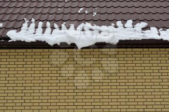 Snow slips down from the roof of the house in spring