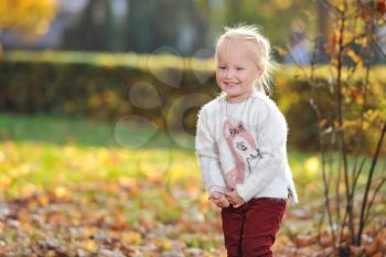 Little blonde girl child on autumn Park background while walking