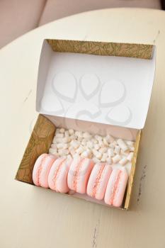 Macaroons and marshmallow in a box on a vintage table.