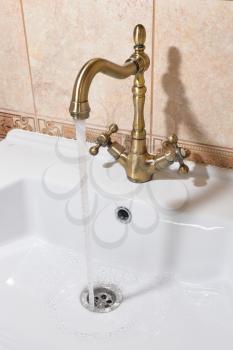 Water flows from the bronze faucet into the sink.