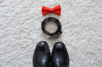Male accessories on a white carpet, shoes, belt, tie
