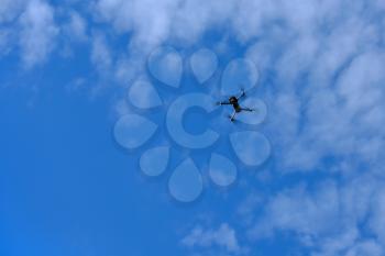 Drone flies high in the blue sky.