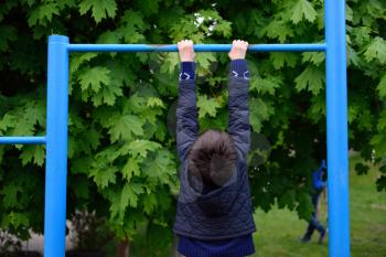 Child hanging on a horizontal bar in the Playground