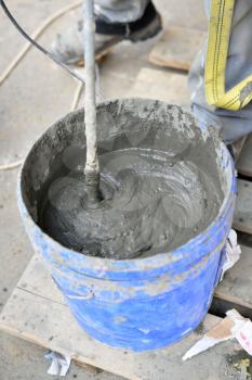 Mixing cement with a mixer in a bucket on the street.