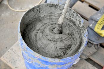 Mixing cement with a mixer in a bucket on the street.