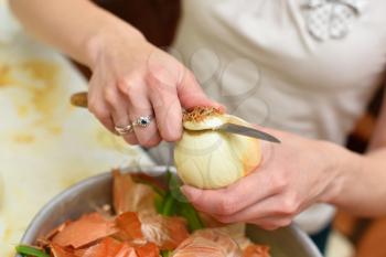 Woman is brushing a fresh onion over a cup.