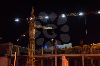 Large construction crane works at night. Night shift construction.